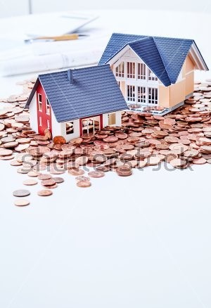 stock-photo-miniatures-of-two-houses-standing-among-coins-683983537